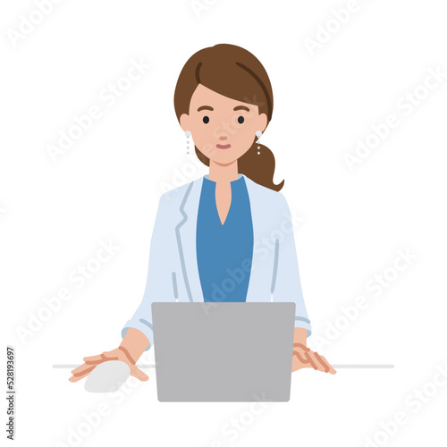 デスクで座ってPCを使っているジャケットの女性