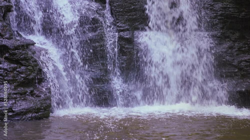 Slow motion medium shot of cascading waterfalls over rock.