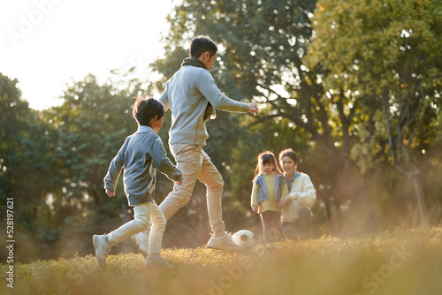 Fototapeta Naklejka Na Ścianę i Meble -  young asian family with two children enjoying outdoor sport in park