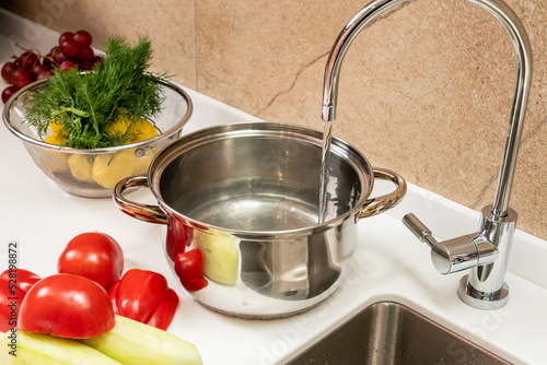 Water is drawn into a pot on the table next to the sink and cooked vegetables