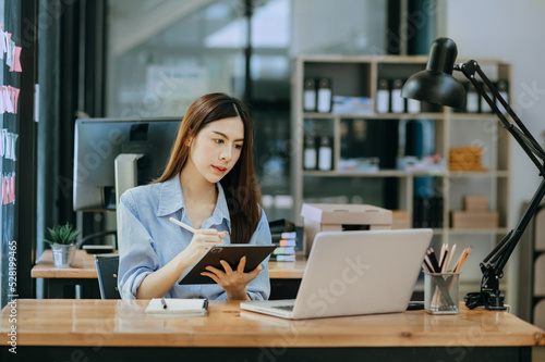 Woman freelancer is working her job on computer tablet and laptop Doing accounting analysis report real estate investment data, Financial at office.