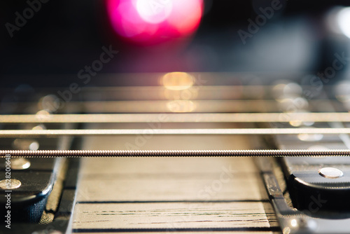 Details of the body and fretboard of an electric guitar. Stage lighting  light music.
