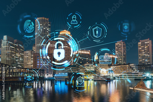 City view panorama of Boston Harbor and Seaport Blvd at night time, Massachusetts. Building exteriors of financial downtown. Glowing Padlock hologram. Concept of cyber security to protect information