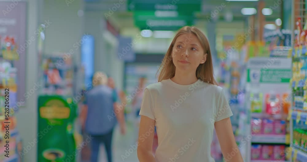 Portrait, beautiful woman walks through the supermarket and smiles. Young woman looks at the goods, shopping for groceries in the store. 4k, ProRes Portrait, beautiful woman walks through the supermarket and smiles. Young woman looks at the goods, shopping for groceries in the store. 4k, ProRes