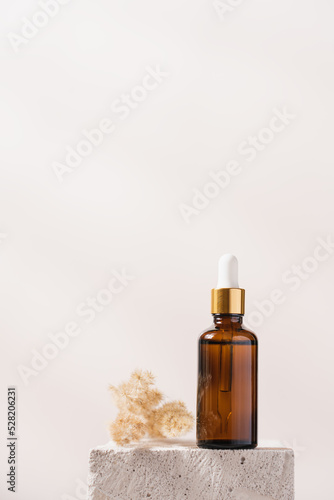 Serum in glass bottle with pipette stands on concrete stone podium on white background. Beauty skin care concept