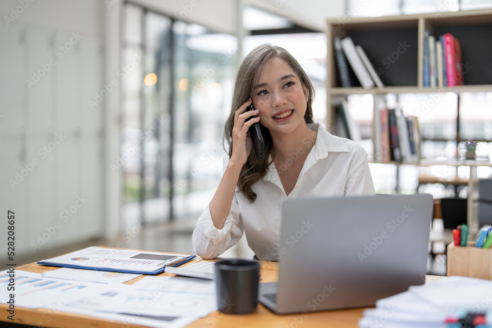 Happy businesswoman talking on mobile phone while working on laptop computer and analyzing business graph chart. Happy businesswoman talking on mobile phone while working on laptop computer and analyzing business graph chart.