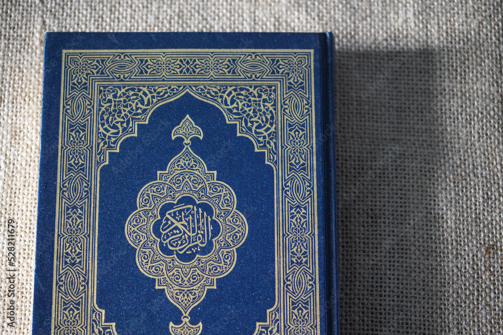 Indonesia - July, 2022 : The Quran, also romanized Qur'an or Koran, is central religious text of Islam, believed by Muslims to be revelation from God (Allah). Classical Arabic. Sack, blue.