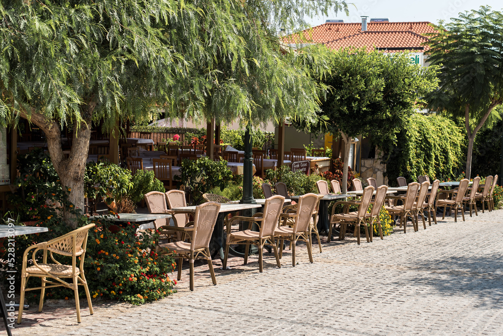 Chairs and tables on the Greek taverna put along the main footpath in Skala, Kefalonia, Ionian islands region of Greece.