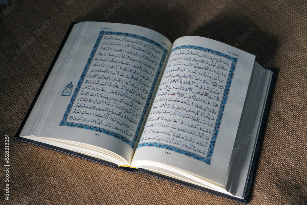 Fototapeta premium Kudus, Indonesia - August, 2022 : The Quran, also romanized Qur'an or Koran, is the central religious text of Islam, believed by Muslims to be a revelation from God (Allah). Brown sack background.
