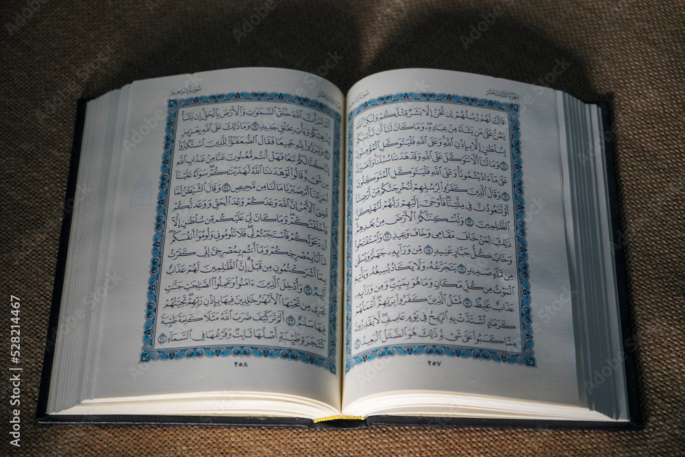 Obraz premium Indonesia - July, 2022 : The Quran, also romanized Qur'an or Koran, is central religious text of Islam, believed by Muslims to revelation from God (Allah). Classical Arabic. Sack, Blue. white. Open.