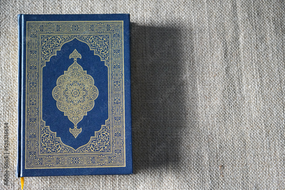 Indonesia - July, 2022 : The Quran, also romanized Qur'an or Koran, is central religious text of Islam, believed by Muslims to revelation from God (Allah). Classical Arabic. Sack, Blue. white. Open. Indonesia - July, 2022 : The Quran, also romanized Qur'an or Koran, is central religious text of Islam, believed by Muslims to revelation from God (Allah). Classical Arabic. Sack, Blue. white. Open.