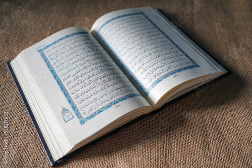 Kudus, Indonesia - August, 2022 : The Quran, also romanized Qur'an or Koran, is the central religious text of Islam, believed by Muslims to be a revelation from God (Allah). Brown sack background.