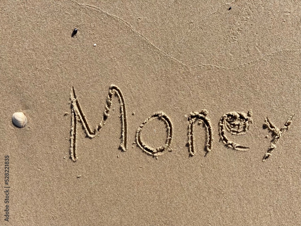 Fototapeta premium on the beach is carved with letters in the smooth sand the writing Money