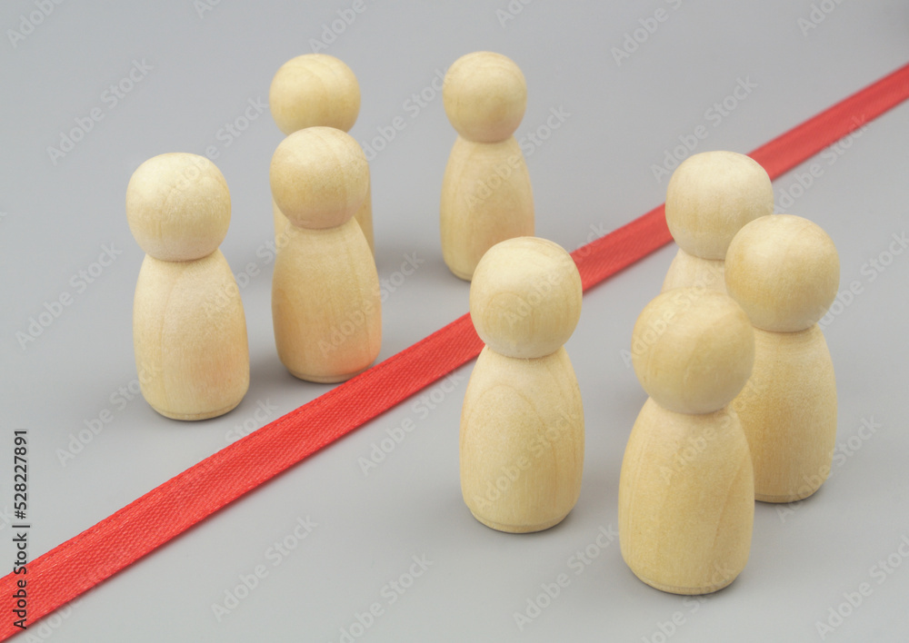 Obraz premium Separating people, borders between people concept. Wooden figures separated by red line or border.