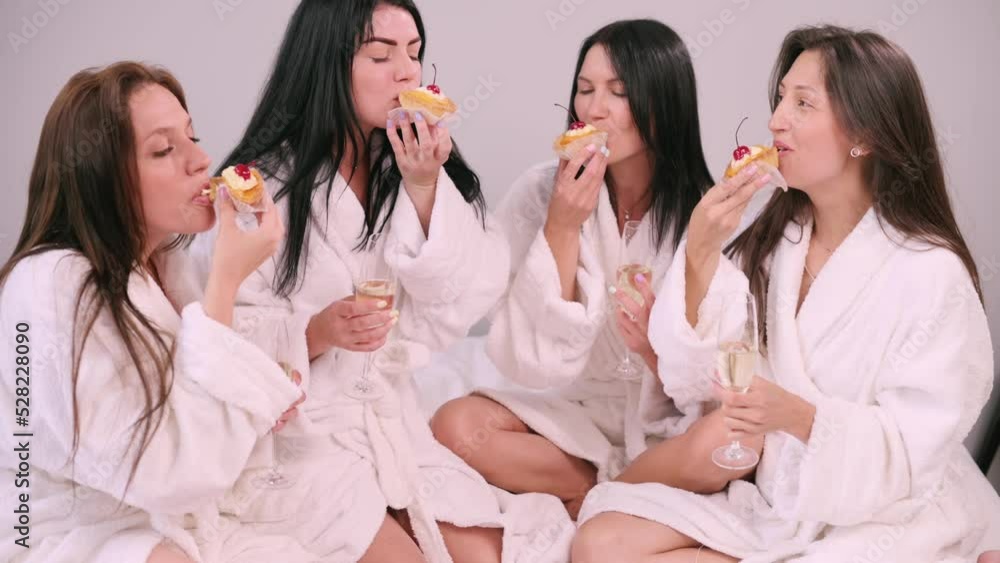 Girlfriends are having fun. Four young attractive women in bathrobes eat sweets in bed. Girlfriends are having fun. Four young attractive women in bathrobes eat sweets in bed.