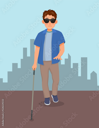 Young blind man in dark glasses walking with a cane stick on the street