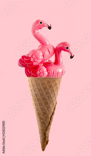 Two inflatable flamingo in waffle cone on pink background. Minimal  art summer creative poster. photo