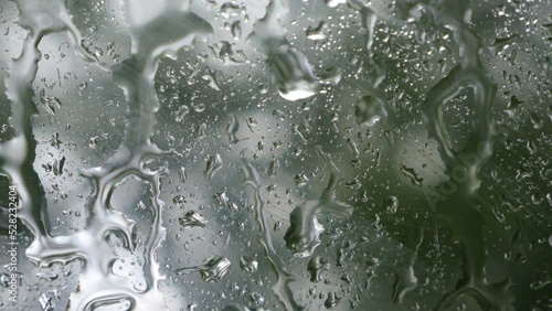 Detalle de gotas de lluvia deslizándose sobre el cristal de un coche en un día de tormenta. photo