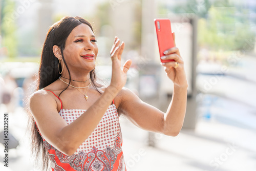 Trans woman waving at the mobile while doing video call