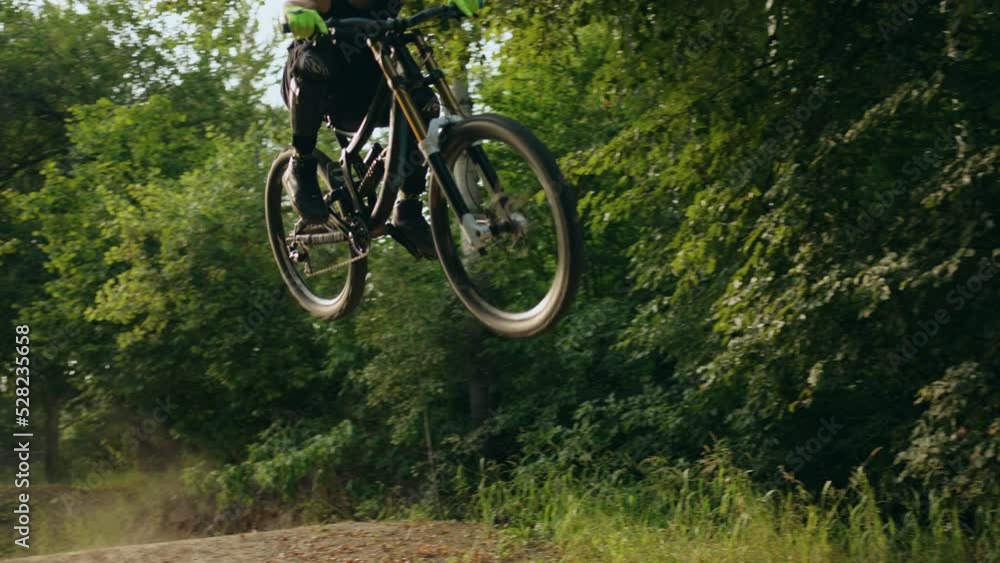 MTB racer training bike tricks in forest, riding on road and jumping up, slow motion, active hobby MTB racer training bike tricks in forest, riding on road and jumping up, slow motion, active hobby
