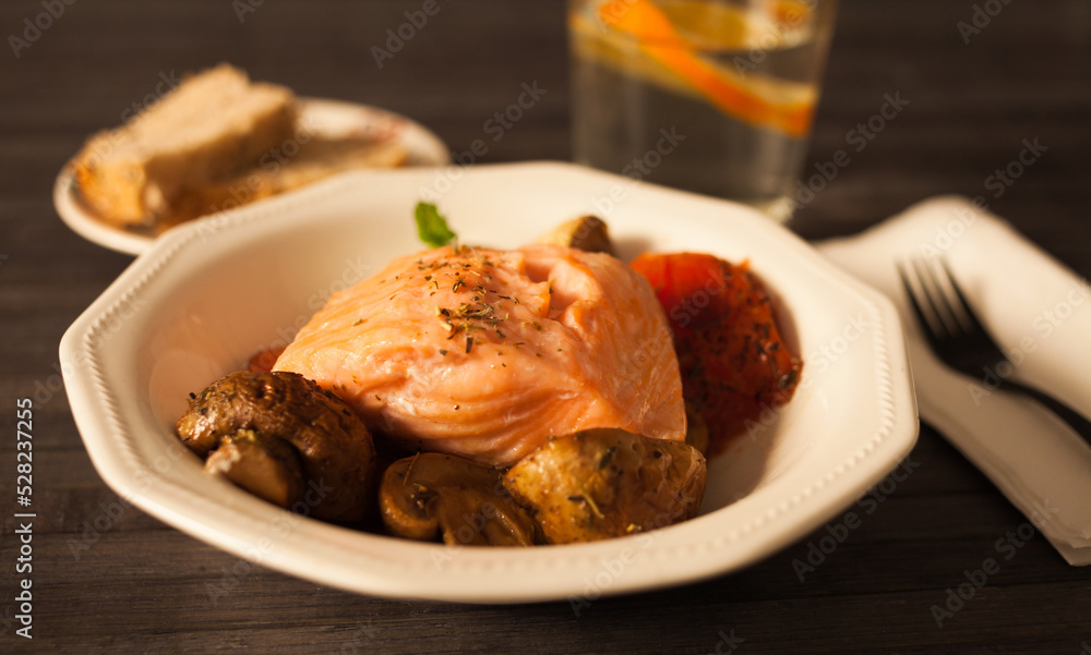 steamed salmon fillet on a pillow of fried mushrooms and tomatoes in a white bowl
