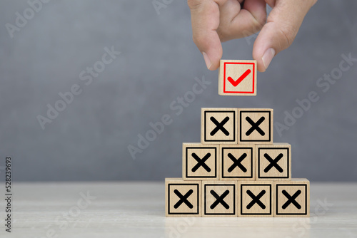 Hand choose wooden block stack with check mark and cross symbol for customer survey service and feedback. photo