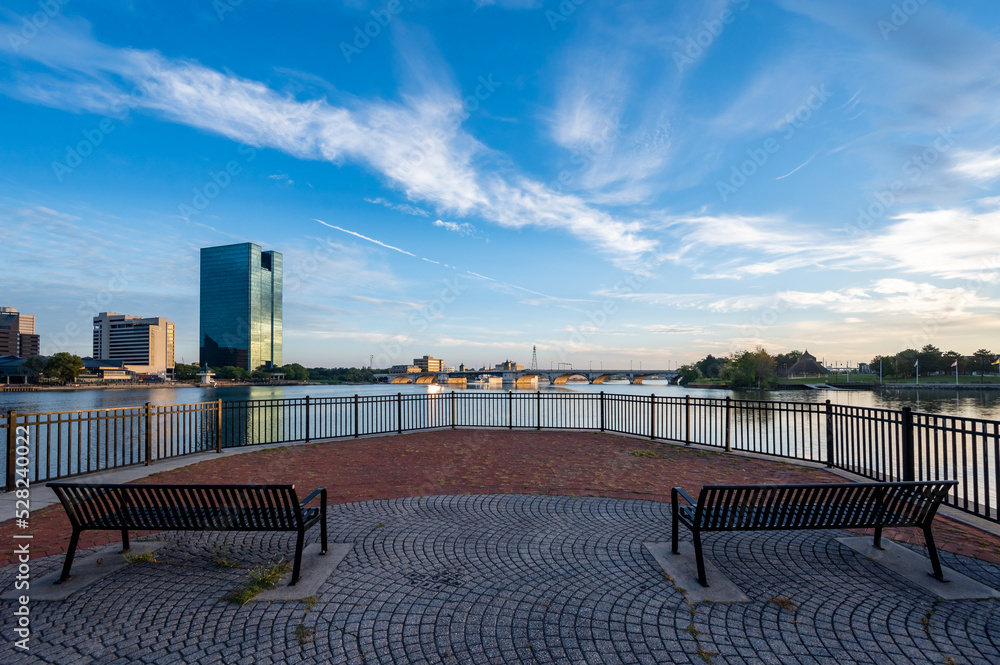 Reflection of downtown Toledo Ohio skyline during sunrise from international park with a foreground of two benches and brick patterns 