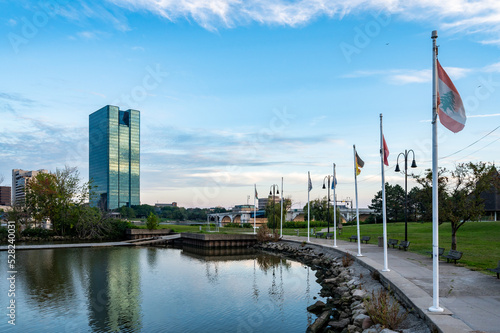 Reflection of downtown Toledo Ohio skyline during sunrise from international park with a leading line of flags