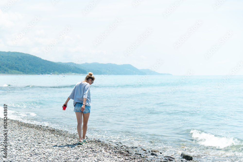 A young woman with a cup of coffee on the beach. Summer. Vacation.