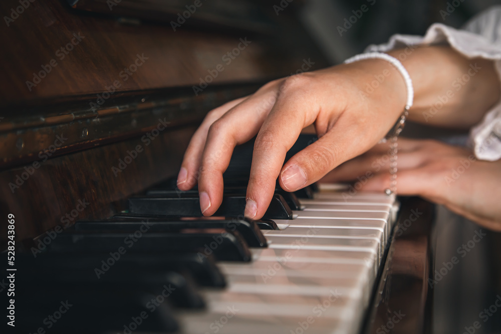 Female hands playing the old piano, close-up.