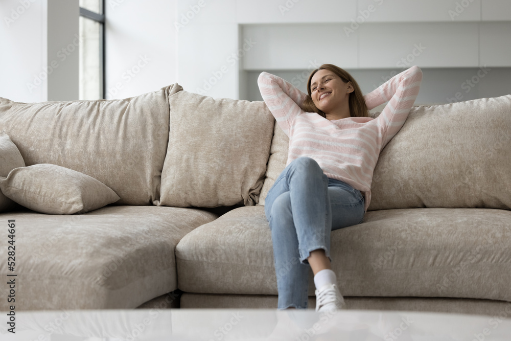 Joyful happy relaxed pretty girl resting on soft couch at home, looking away, smiling, laughing, enjoying relaxation, leisure, comfort, laziness, dreaming, thinking Joyful happy relaxed pretty girl resting on soft couch at home, looking away, smiling, laughing, enjoying relaxation, leisure, comfort, laziness, dreaming, thinking