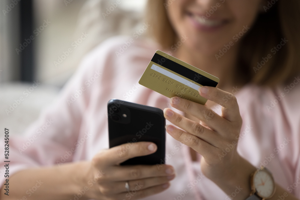 Satisfied bank customer woman using credit card and banking app mobile phone, making online payment, money transaction, paying on Internet store website. Object close up, cropped shot Satisfied bank customer woman using credit card and banking app mobile phone, making online payment, money transaction, paying on Internet store website. Object close up, cropped shot