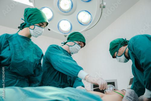 Group of male and female team of surgeon wearing scrub  mask and headscarf with gloves operating young woman in operation theatre in modern hospital