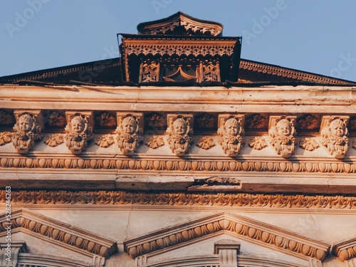 Beautiful the 19th century house. Russian rural architecture in Vladimir. Stucco molding, bas-reliefs. Wooden window shutters, Pseudo Russe Style. Crying and laughing babies face sculpture, nalichniki