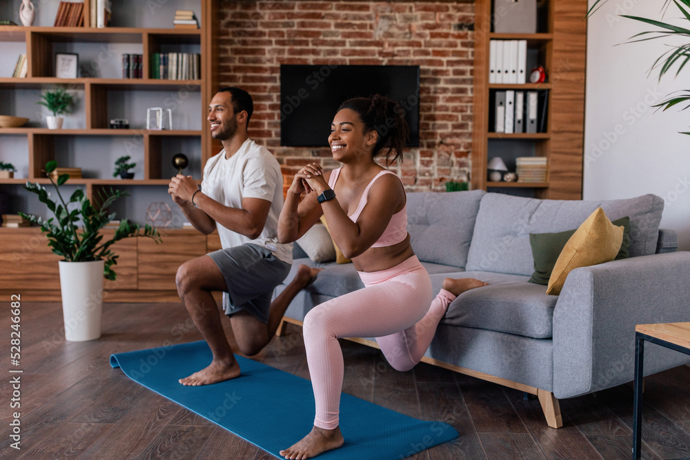 Obraz premium Happy young african american family in sportswear doing leg exercises, stretching or practicing yoga