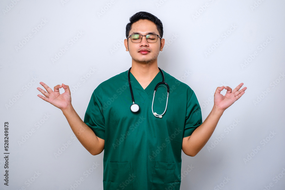 Calm and patient asian male doctor, nurse in scrubs staying relaxed, meditating with eyes closed and happy smile Calm and patient asian male doctor, nurse in scrubs staying relaxed, meditating with eyes closed and happy smile