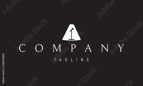 Vector logo on which an abstract image of a microphone on a stand on a stage in a spotlight.