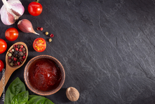 Tomato sauce and spice at black slate background table. Natural healthy homemade food concept