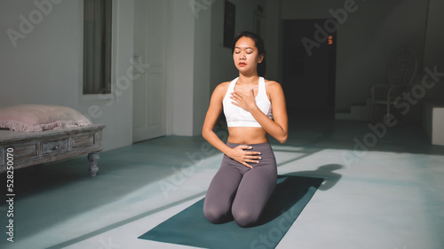 Asian girl practicing yoga at spacious home