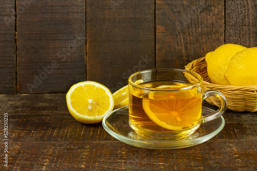 Cup of hot tea and fresh lemon on rustic wooden table.