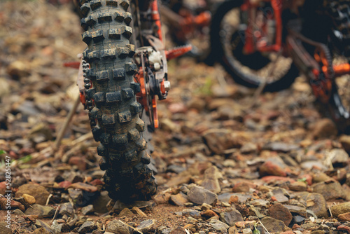 Part of a motocross wheel on a rocky road, with copy space for your individual text. A part of a dirt road dirt motorbike in the forest.