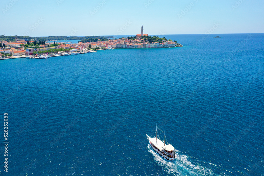 Beautiful boat travelling towards the Croatian town of Rovinj in the background during summertime.