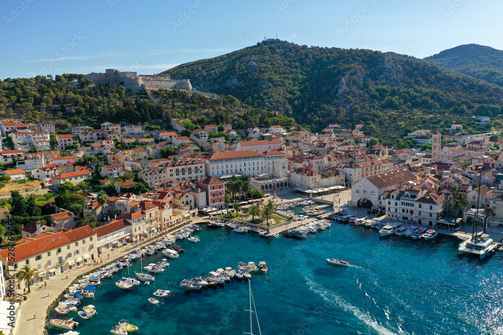 Croatian Island Hvar Harbor in Summertime with multiple moored Yachts and boats. Hisanjola Fort overlooking the water.