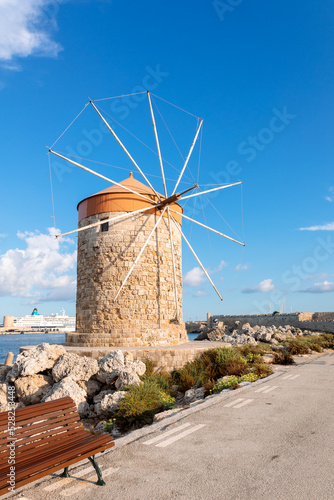 Colorful panoramic view of windmills with yachts in Mandraki harbor at sunset, Rhodes Greece. High quality photo