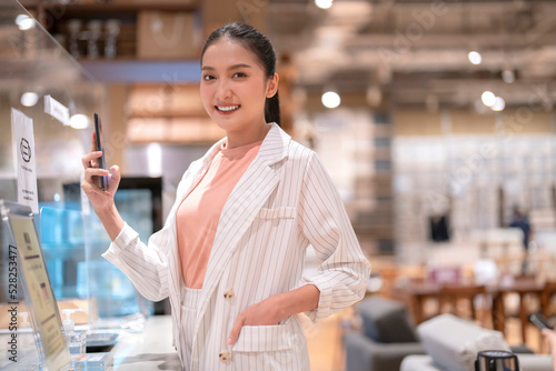 attractive adult asian female cashless online payment smartphone application progress purchase scanning qr code by touchless device new lifestyle shopping in cafe coffee shop store cashier counter photo