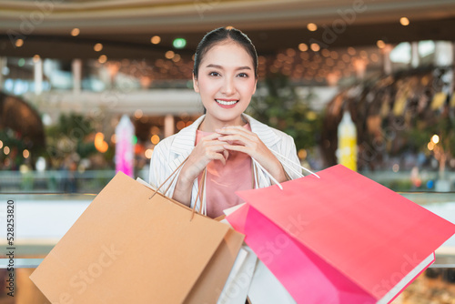 surprising cheerful asian female adult woman shopper hand hold shopping bag happiness lifestyle walking buying cloths in department store shopping mall with happiness exited toothy smiling joyful