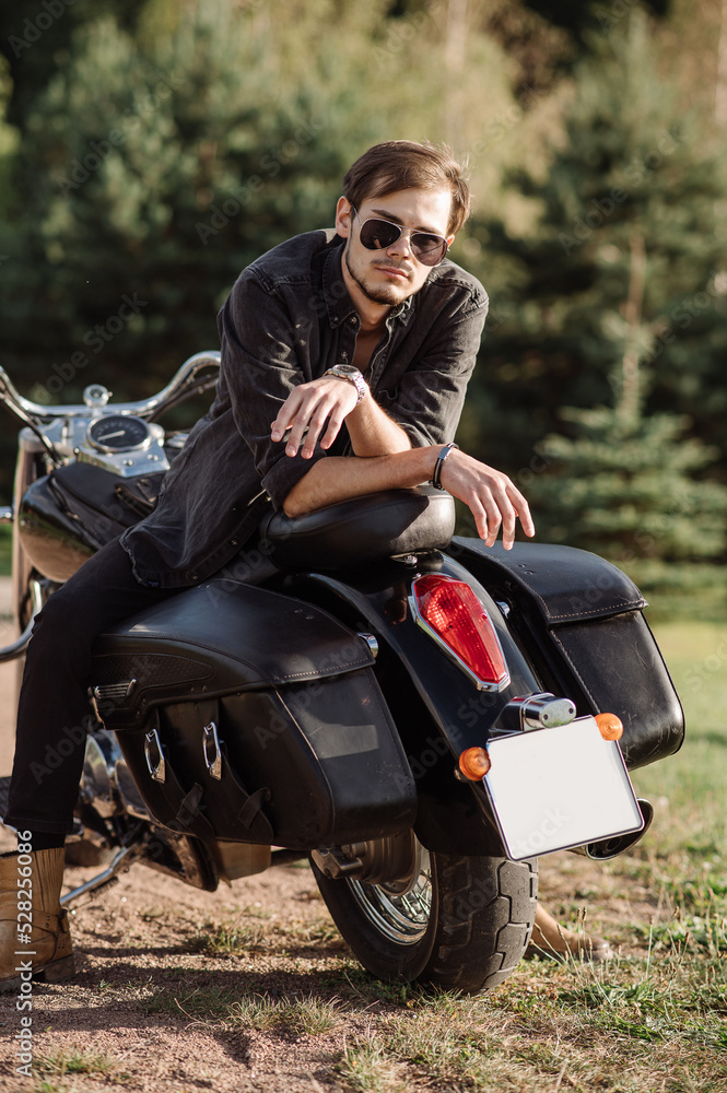 Young handsome male is sitting on his motor bike outdoors Young handsome male is sitting on his motor bike outdoors