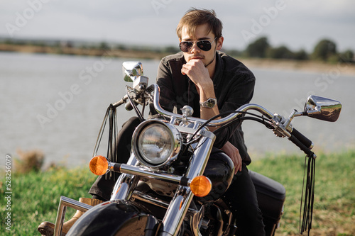 Print op canvas Handsome man or young biker sitting and chilling on the bike chopper outdoors