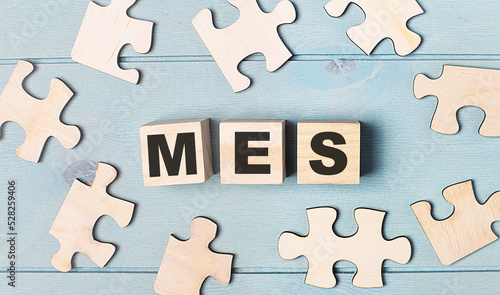 Blank puzzles and wooden cubes with the text MES Manufacturing Execution System lie on a light blue background.
