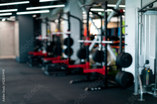 Blurred Background Of Modern Sport Club Interior With Heavy Weight Lifting Equipment